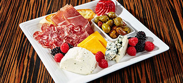 Artisan meat and cheese platter on white ceramic plate