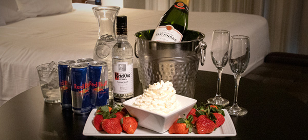 Table with strawberries and whipped cream in front of a bucket of champagne, Ketel One vodka, Red Bull, ice water, and champagne glasses